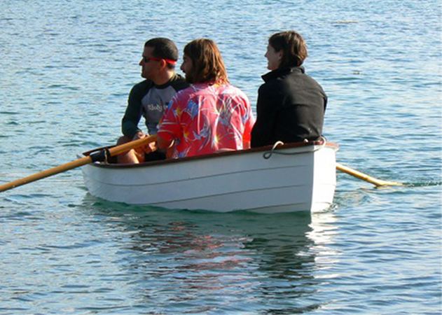 Three people in the stem dinghy as built from a kit