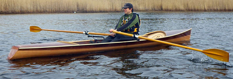 The Noank Pulling Boat is an efficient wooden sculling boat suitable for open water expeditions, using a drop-in sliding seat rowing unit